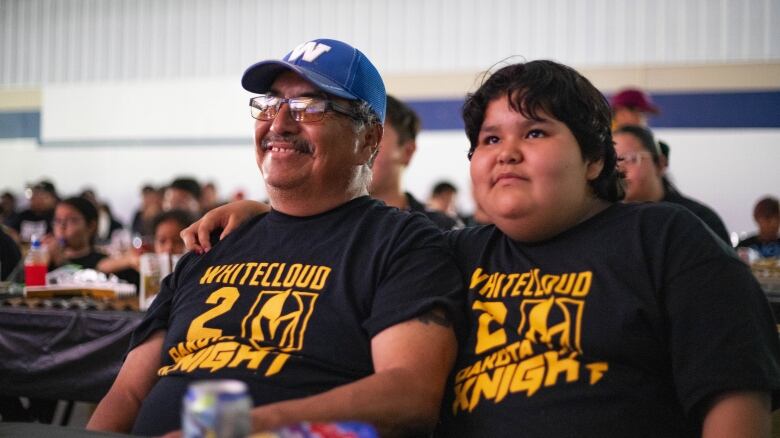 A man and a young person sit smiling wearing Las Vegas Knights t-shirts.