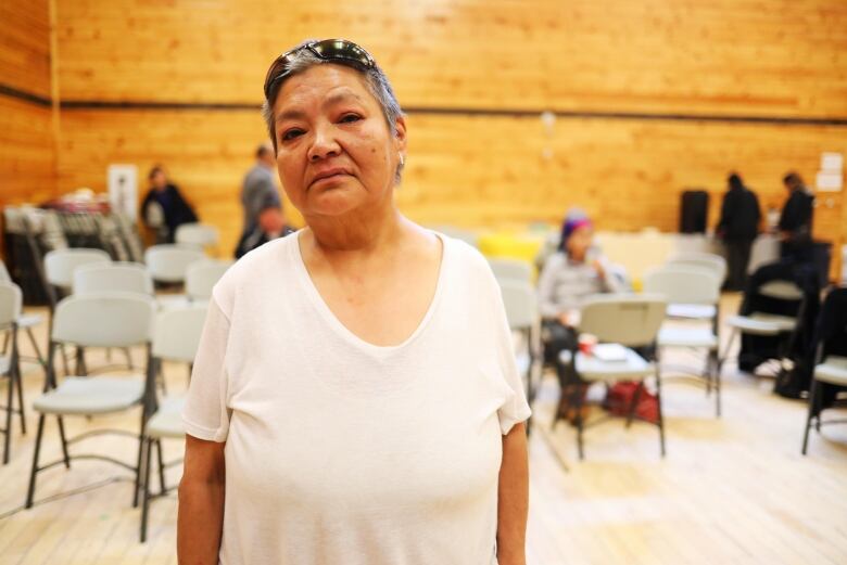 A woman in a white tshirt stands in a large room. 