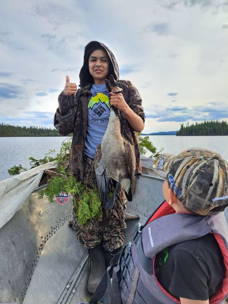 A man in a boat carries a dead goose