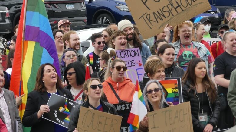 A crowd holding signs and rainbow flags