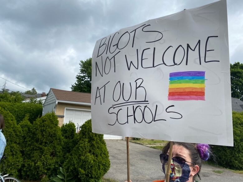 A person stands with a sign.