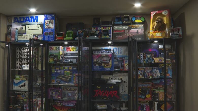 A wall of display cases full of boxed items including a Sega Genesis, a Nintendo system and more.