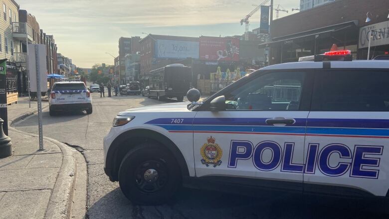 A police cruiser blocking off a section of a street with shops and restaurants. 