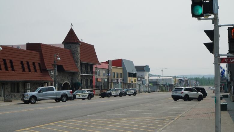 Trucks and police cruisers are parked on a street in Chibougamau, Que. 