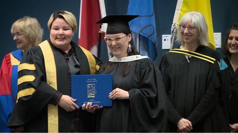 a woman in graduation cap and gown accepting a diploma