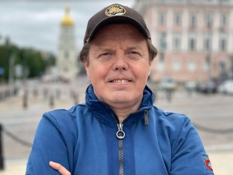 A man wearing a track suit and hat poses for a photo.