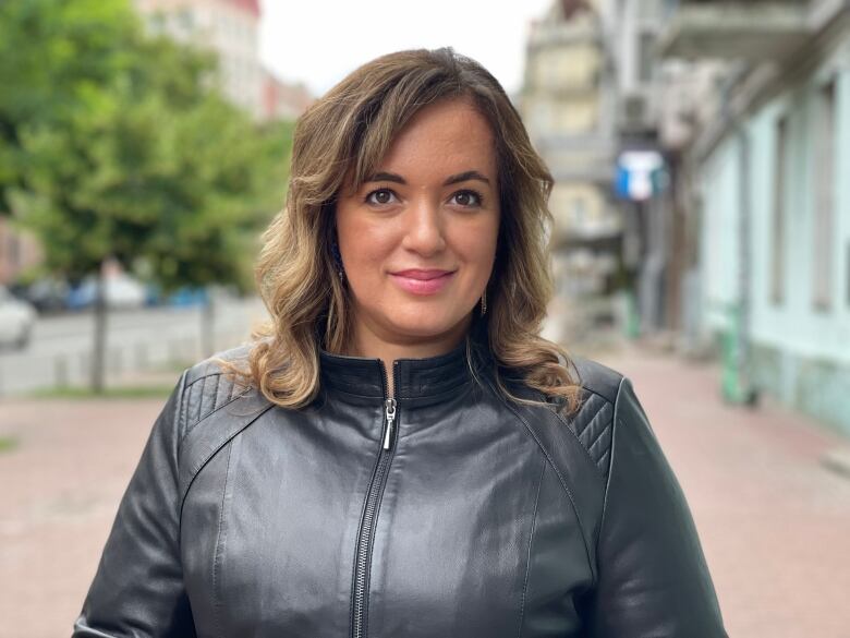 A woman wearing a jacket poses for a photo.