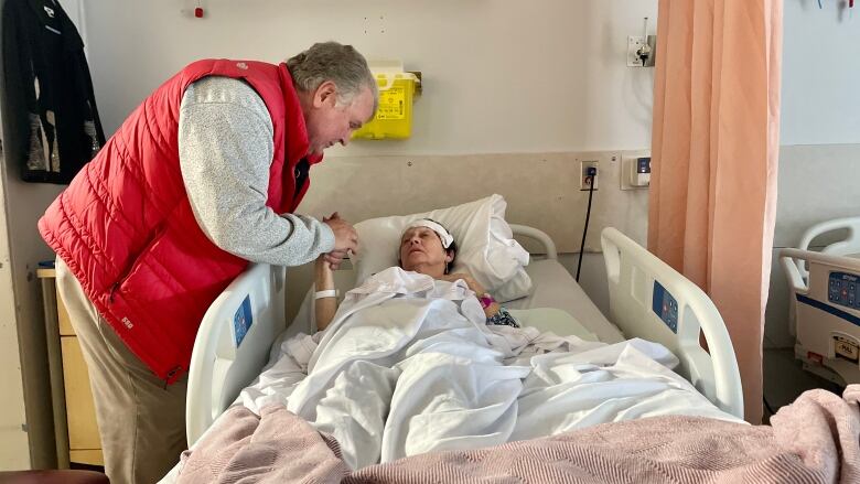 Mike Casey holds his wife's hand while she lays in bed in the Kings County Memorial Hospital.