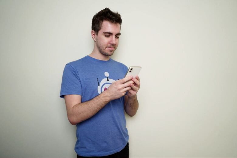 A man in a t-shirt looks at a cell phone.