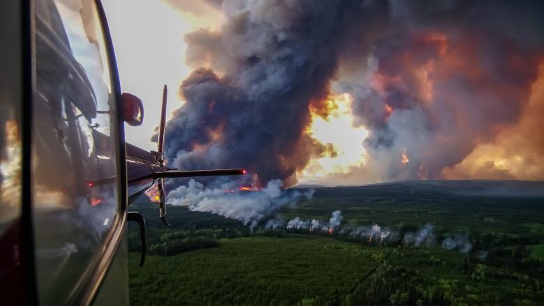 A plane flies over the front lines of the Donnie Creek wildfire.