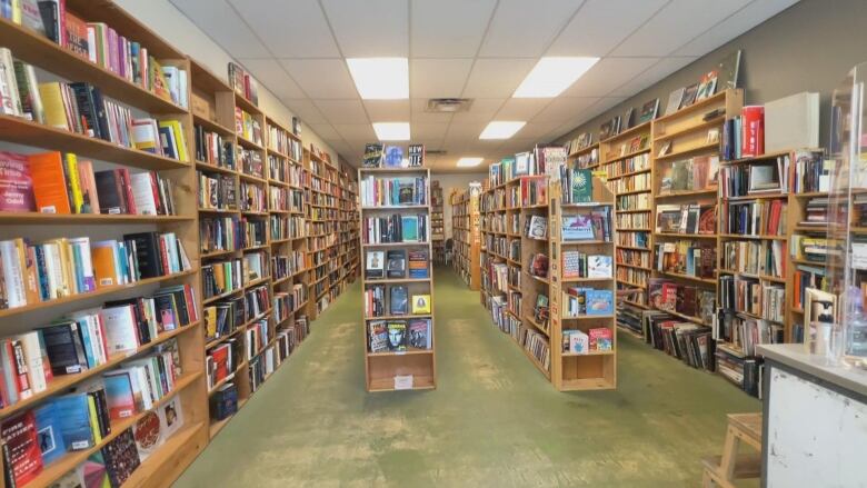 A small bookstore with four rows lined with books is pictured. 