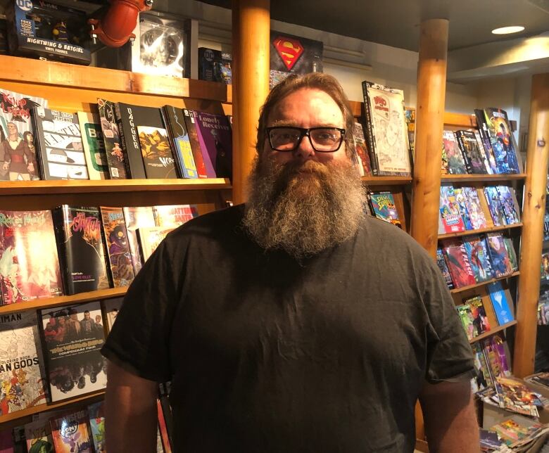 Dylan Miller stands in front of shelves full of comic books.