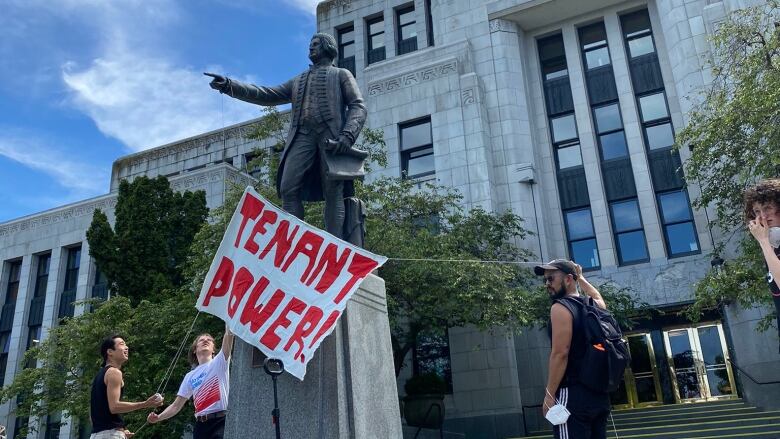 Attendees at a rally against a new development in Vancouver's Chinatown placed a sign on a statue outside City Hall.