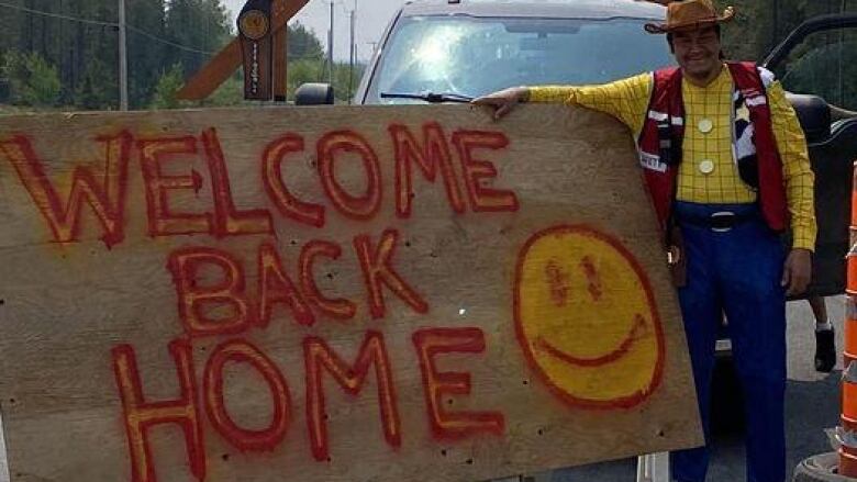 A Cree volunteer in a Woody from Toy Story costume with a painted welcome home sign.