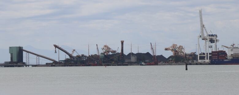 The open ocean is bisected by a long line of steel cranes and gantries.