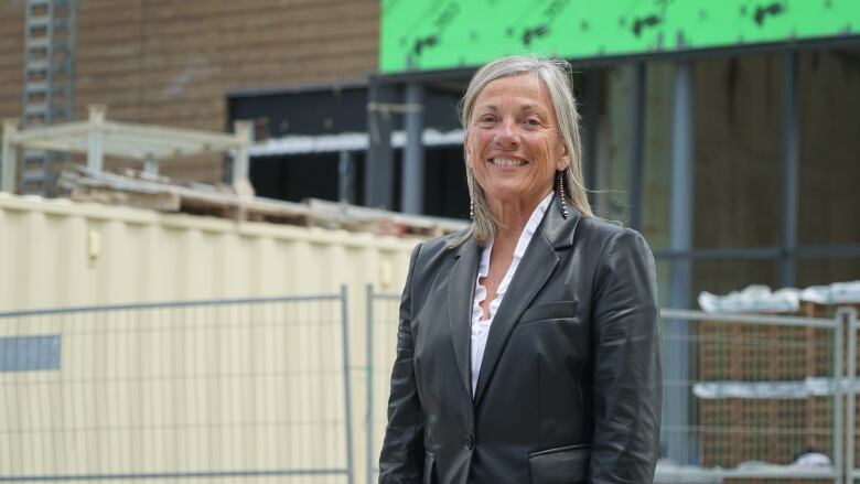 A woman stands in front of a building under construction.