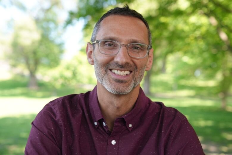 A man smiling in a park.