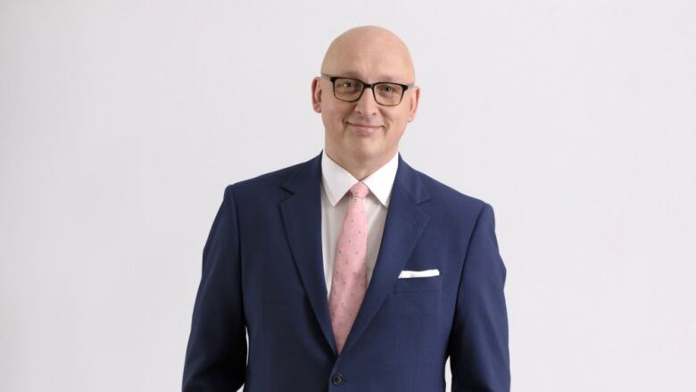 David Cochrane in a dark blue suit, white shirt and pink tie.