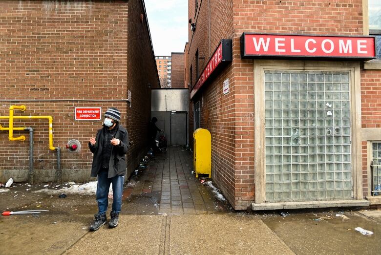 A man stands in front of a homeless shelter.