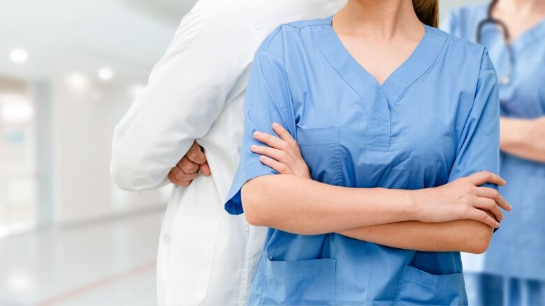 Nurses stand with crossed arms.