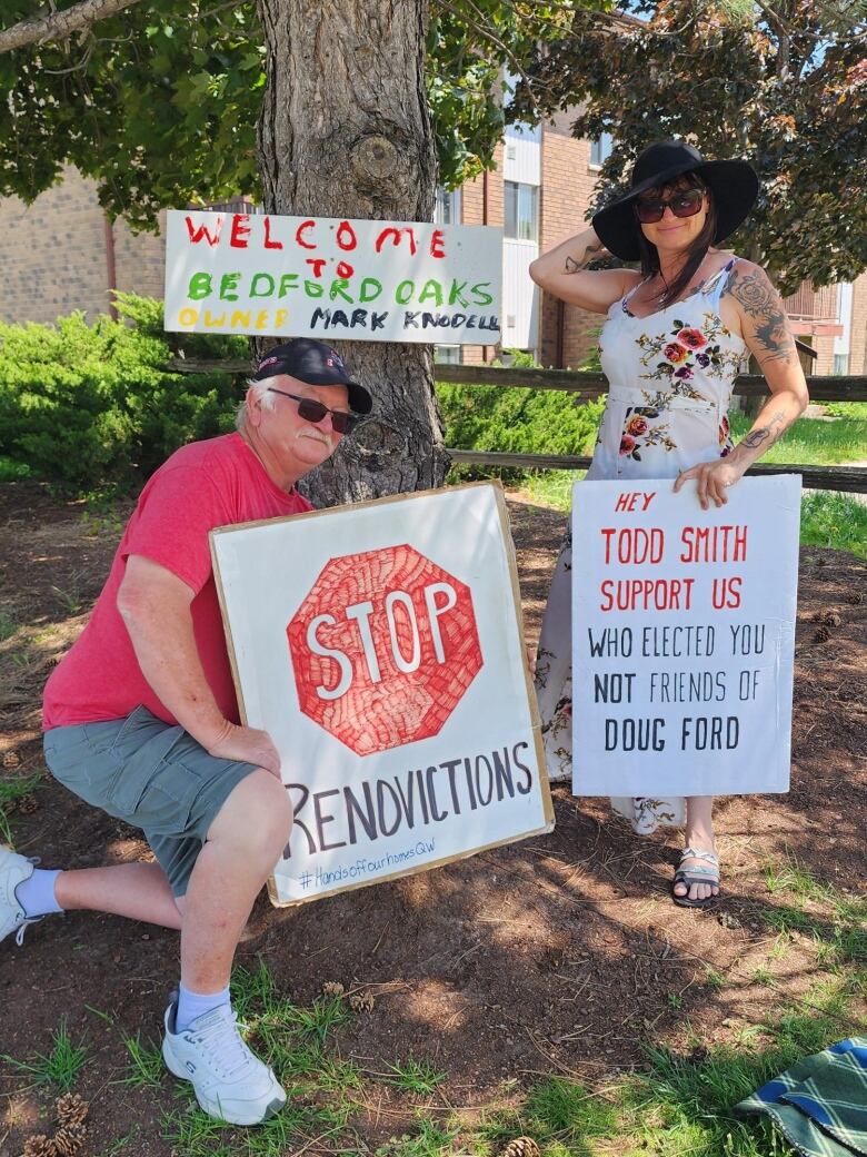 Two people hold protest signs.