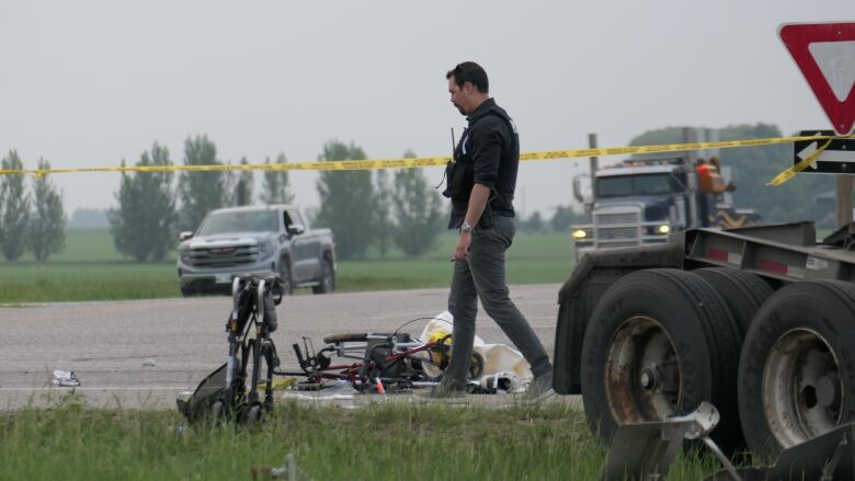 A police officer is shown looking down at walkers on the road following a collision.