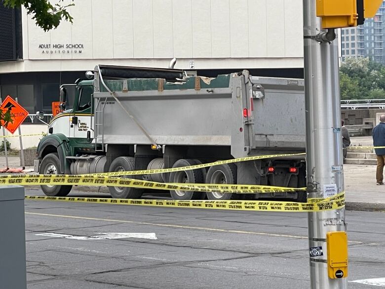 A dump truck sits behind police tape.