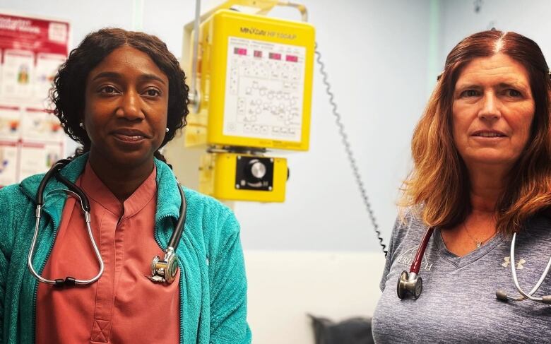 Two women stand side by side inside a clinic room.