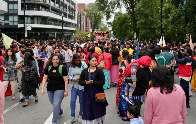 A street is full of hundreds of people walking