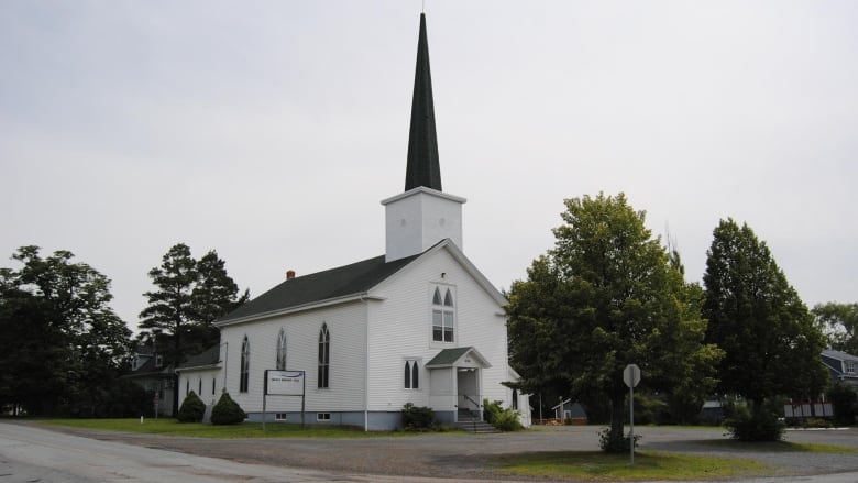 A white wooden church with a tall steeple.