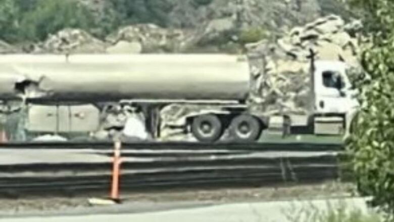 A truck is seen with a hole in its trailer near a rail track.