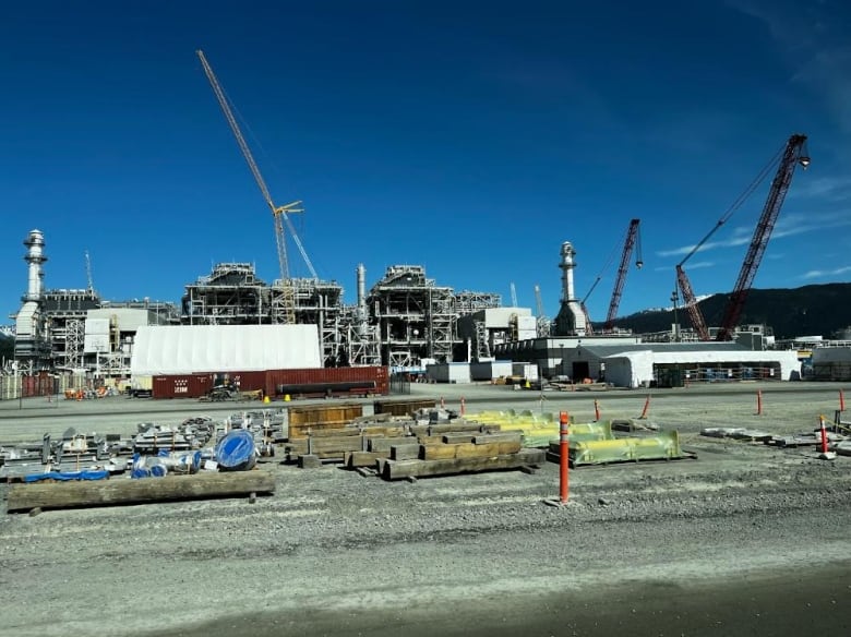 A large factory under construction with mountains in the distance. 