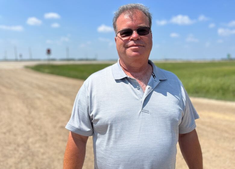 A headshot of a man next to a gravel road.