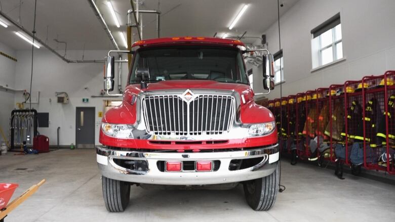 A red fire truck is in the garage with equipment to one side. 