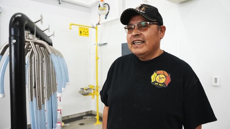 A man in a black tshirt stands in front of a specialty gear dryer. 