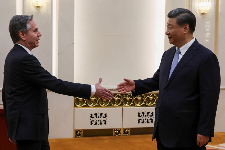 Two men in suits are shown extending their arms for a handshake.