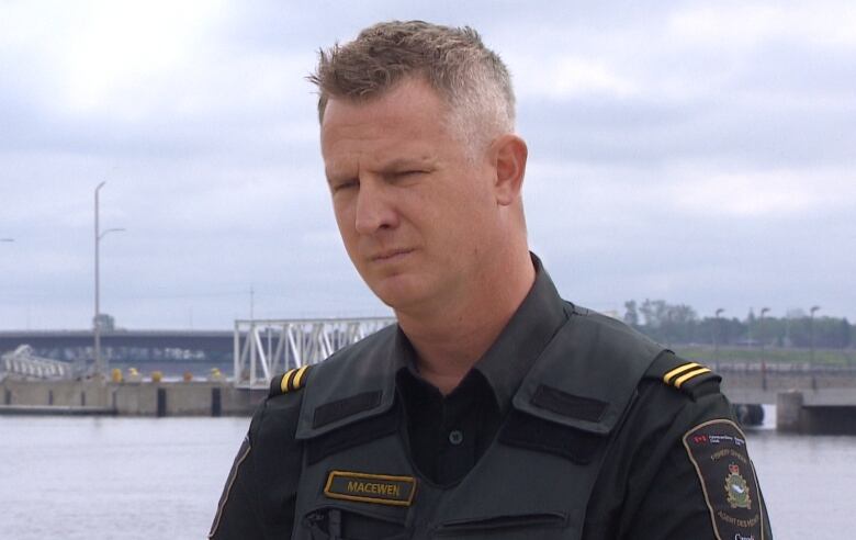 A fisheries enforcement officer in uniform on the waterfront. 