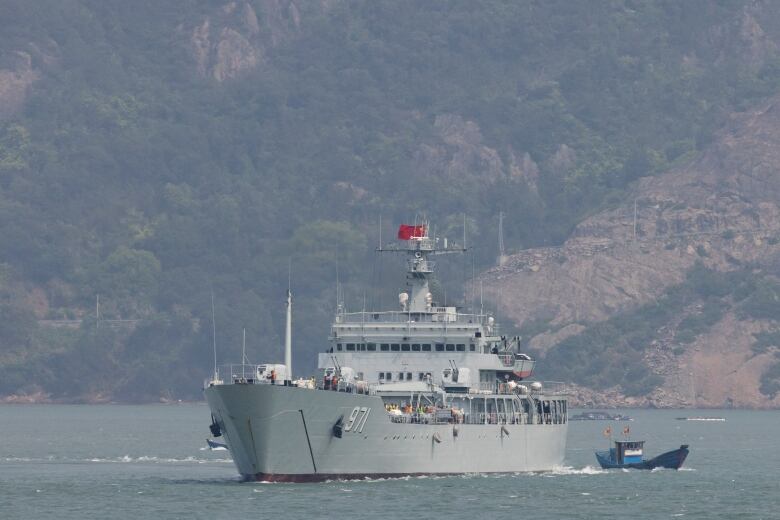 A grey warship is seen sailing off the coast.