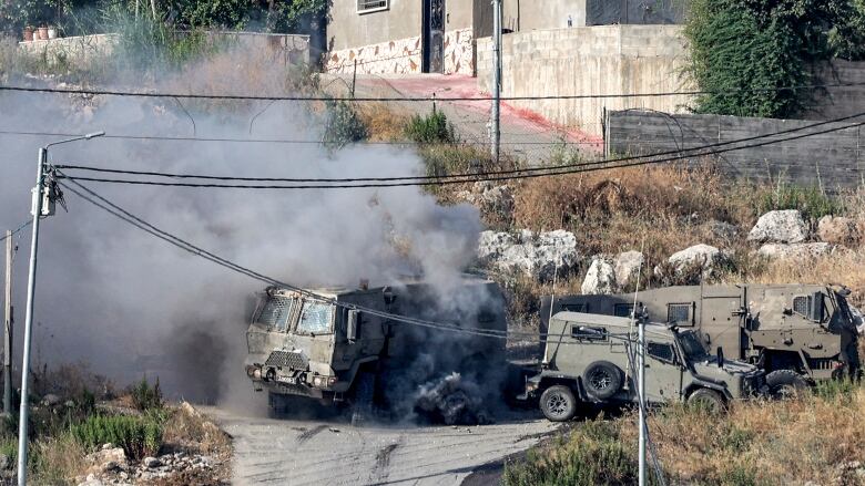 Smoke billows from a military vehicle in the aftermath of an explosion.