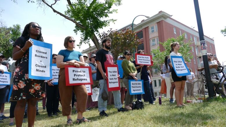 A group of people with signs stand in a lines