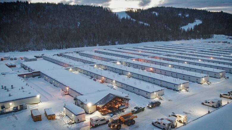 An aerial view shows rows upon rows of long trailers in the snow that make up a work camp of more than 1,000 people.