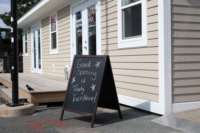 A small sign that says, 'Grand opening of Treaty Truckhouse!' sits outside a small building.