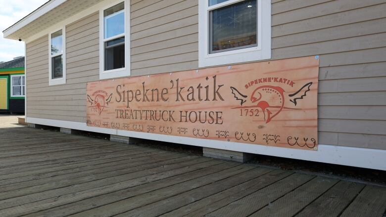 A large wooden sign that says, 'Sipekne'katik Treatytruck House,' is featured on the side of a small building.