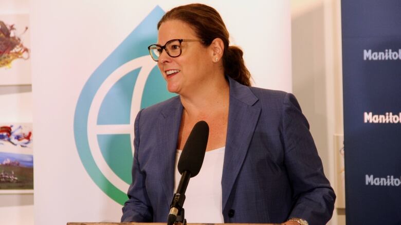 A woman behind the podium at a news conference smiles