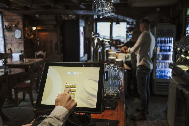 A server inputs information into a cash register system at a restaurant and bar.