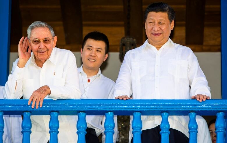 Three men in white shirts stare from balcony.