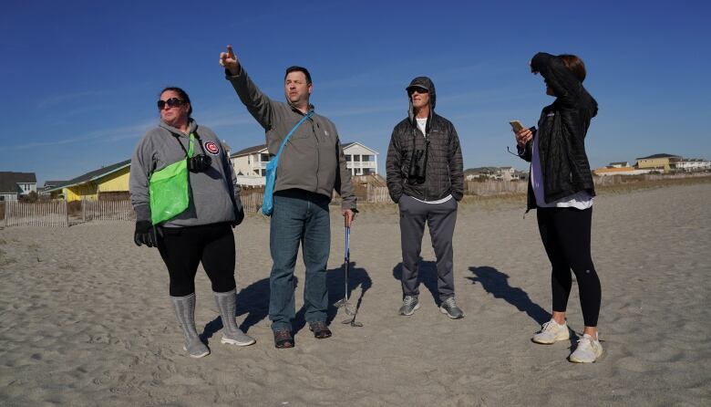 People on beach pointing at sky