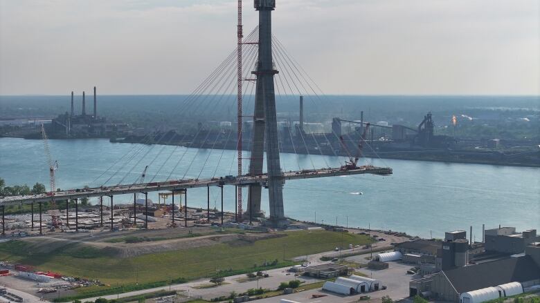 A partially built bridge is shown over the Detroit River.