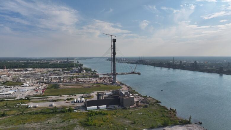 A partially built bridge is shown over the Detroit River.