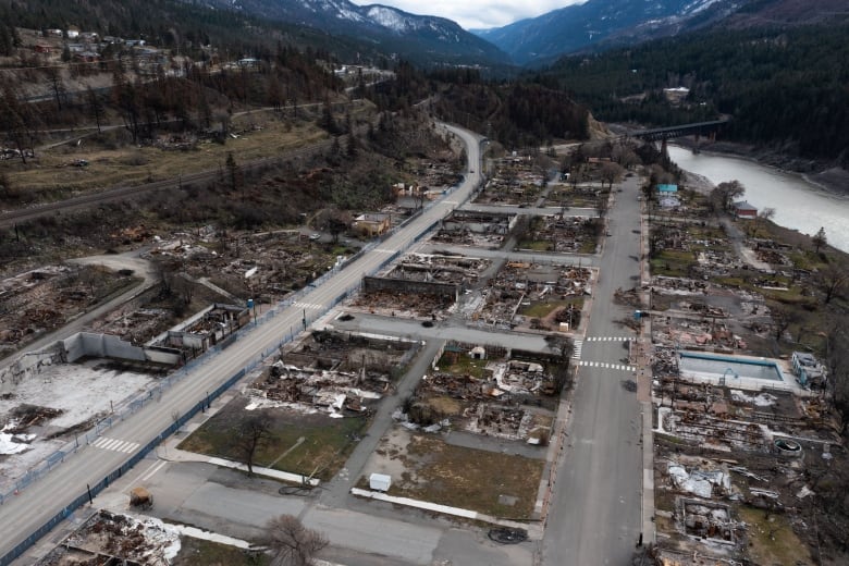 An aerial view of a village virtually destroyed by wildfires, with very few standing structures left.